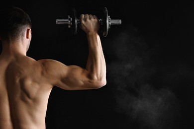 Photo of Man training with barbell on black background, back view. Space for text