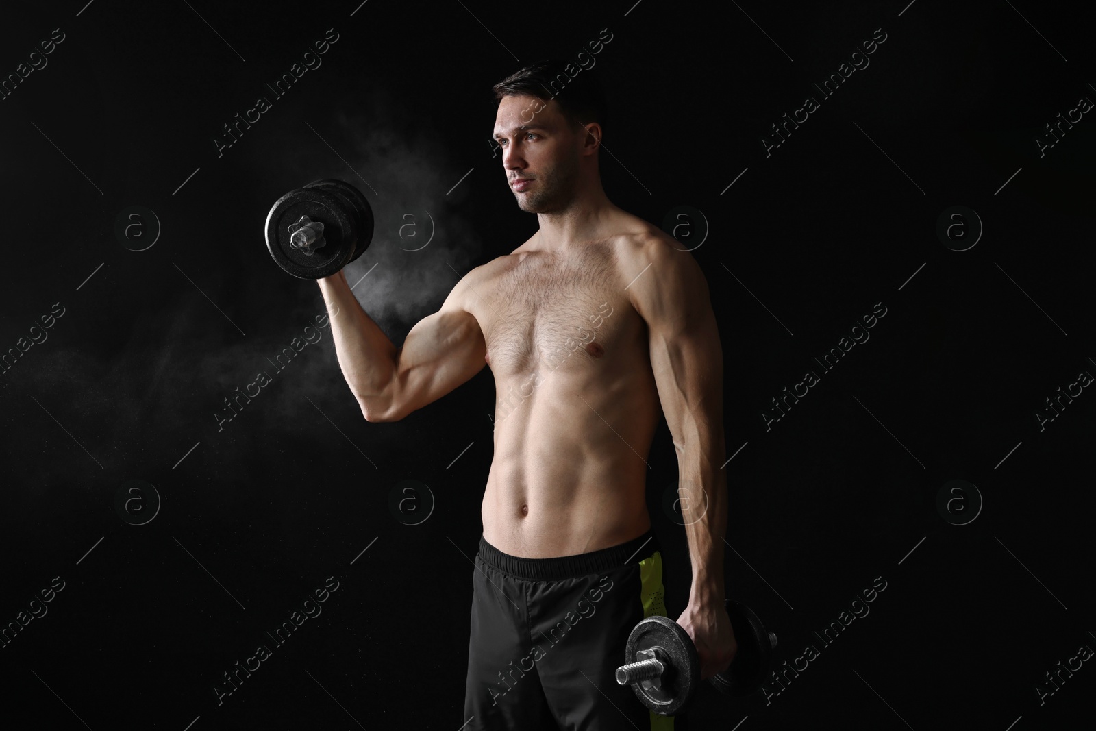 Photo of Man training with barbell on black background