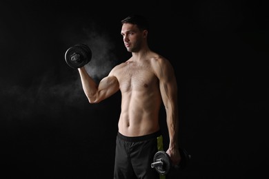 Man training with barbell on black background