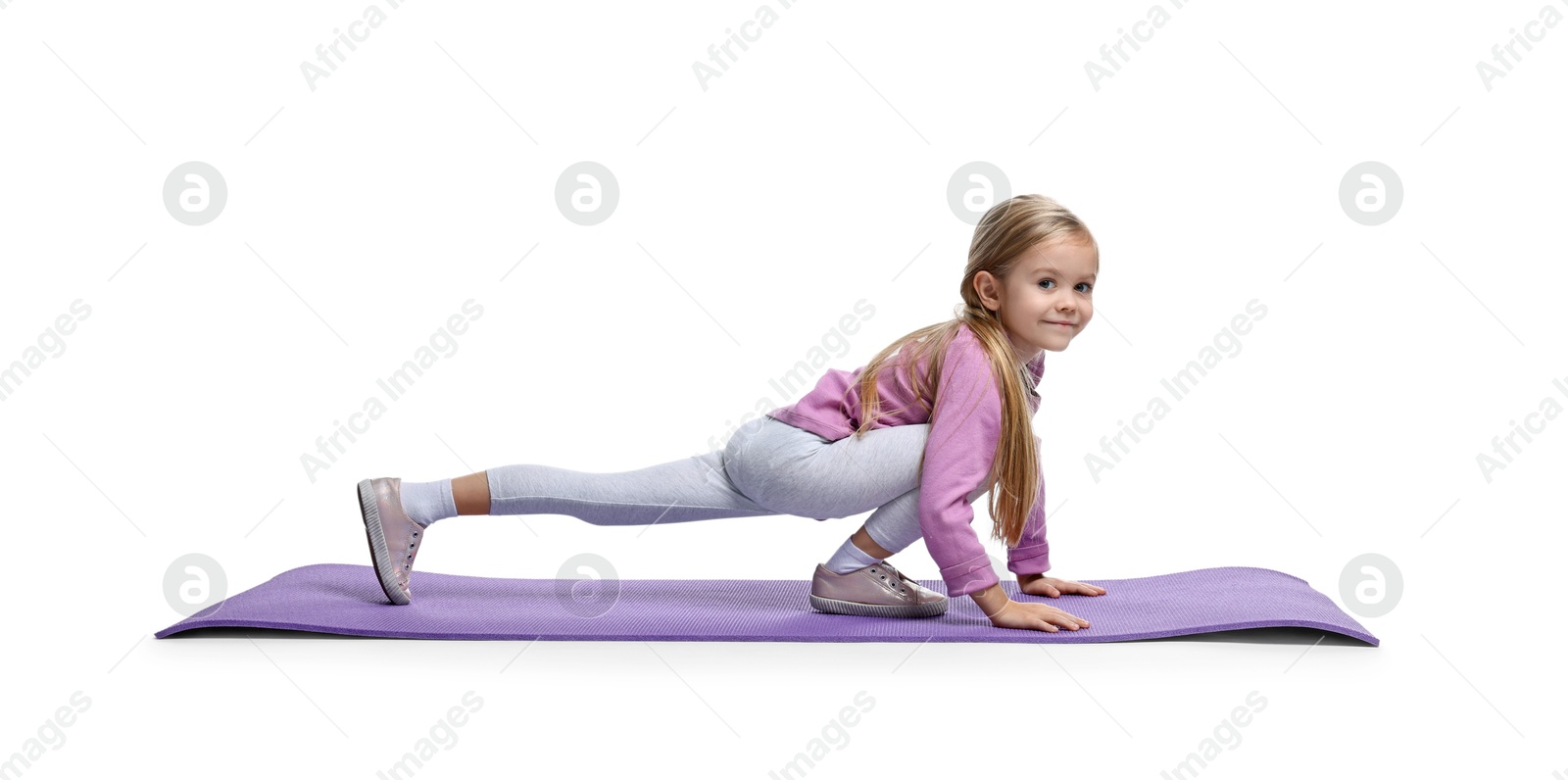 Photo of Little girl exercising on fitness mat against white background. Sport activity