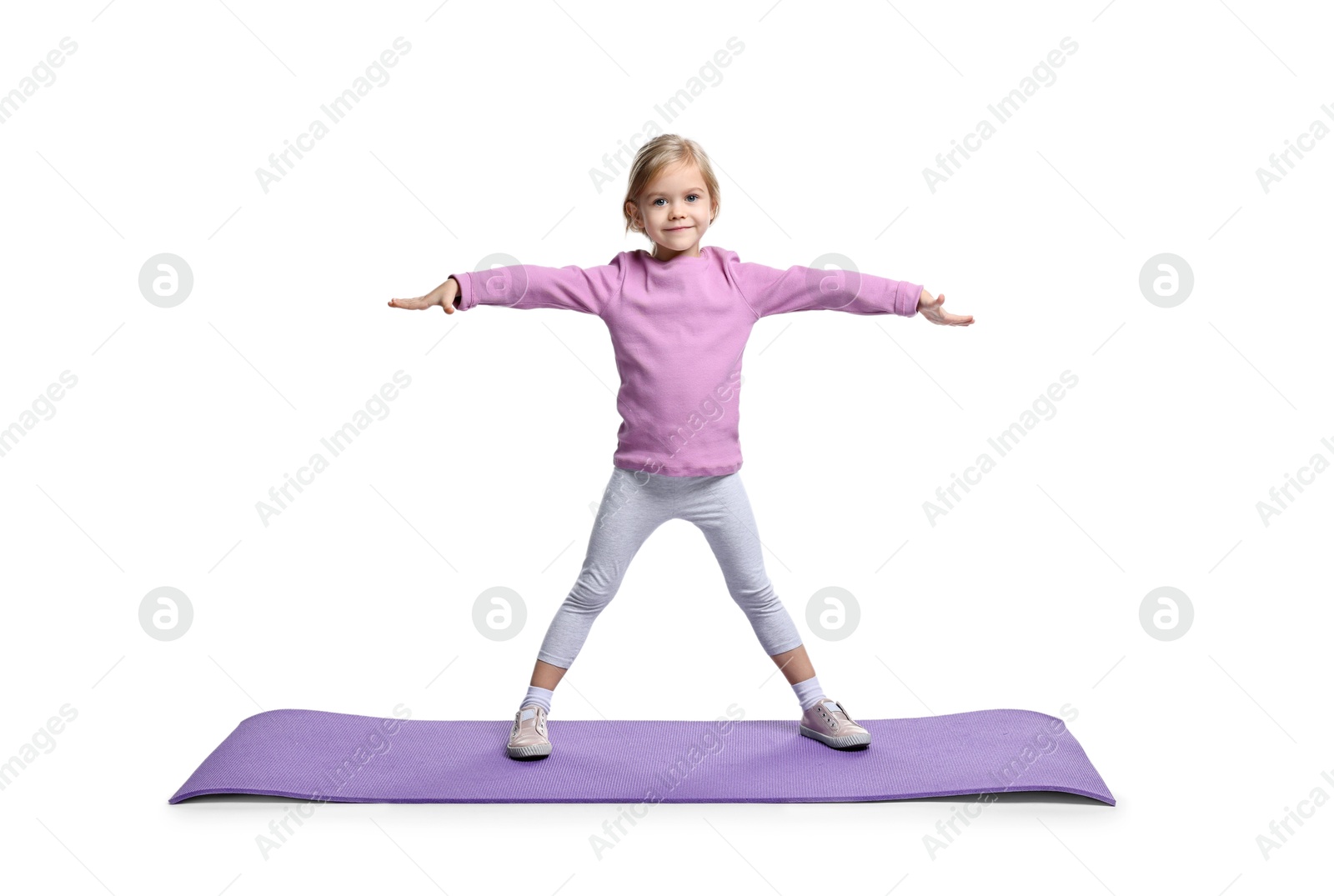 Photo of Little girl exercising on fitness mat against white background. Sport activity