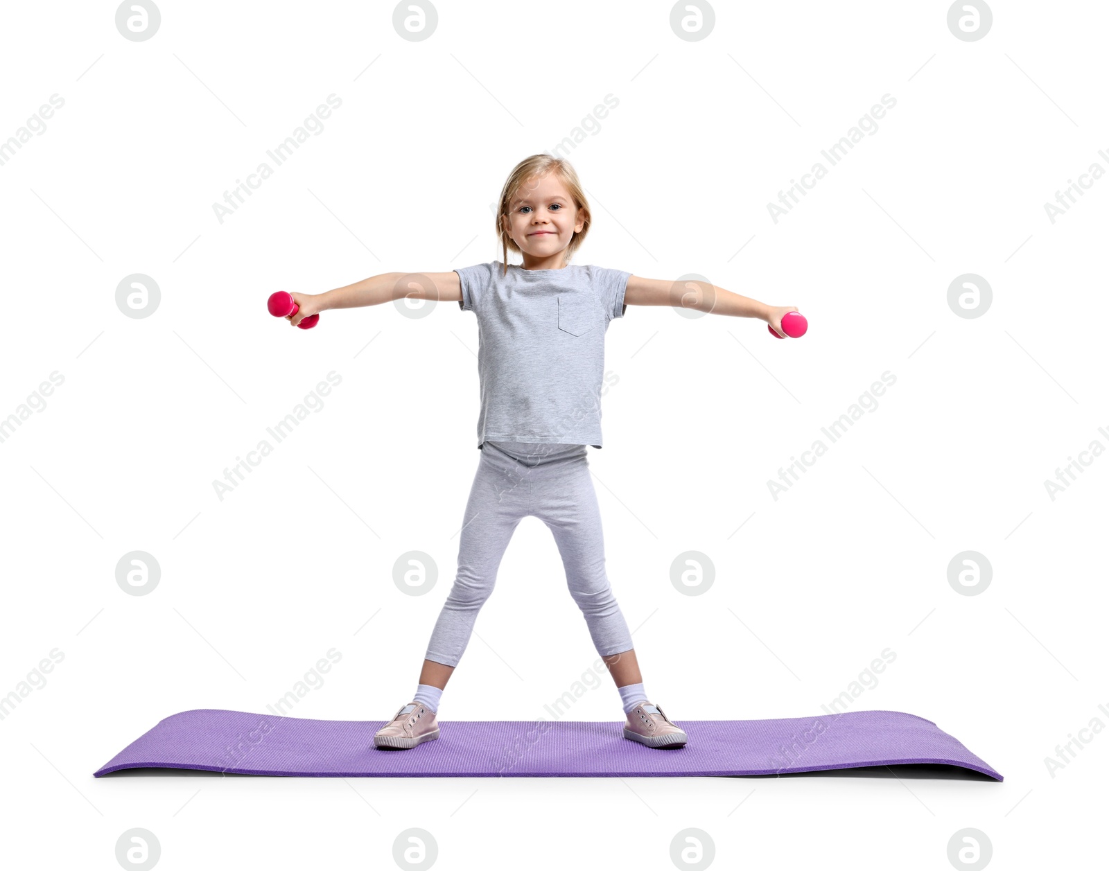 Photo of Little girl exercising with dumbbells on fitness mat against white background. Sport activity