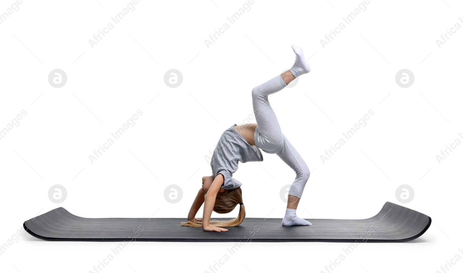 Photo of Little girl exercising on fitness mat against white background. Sport activity