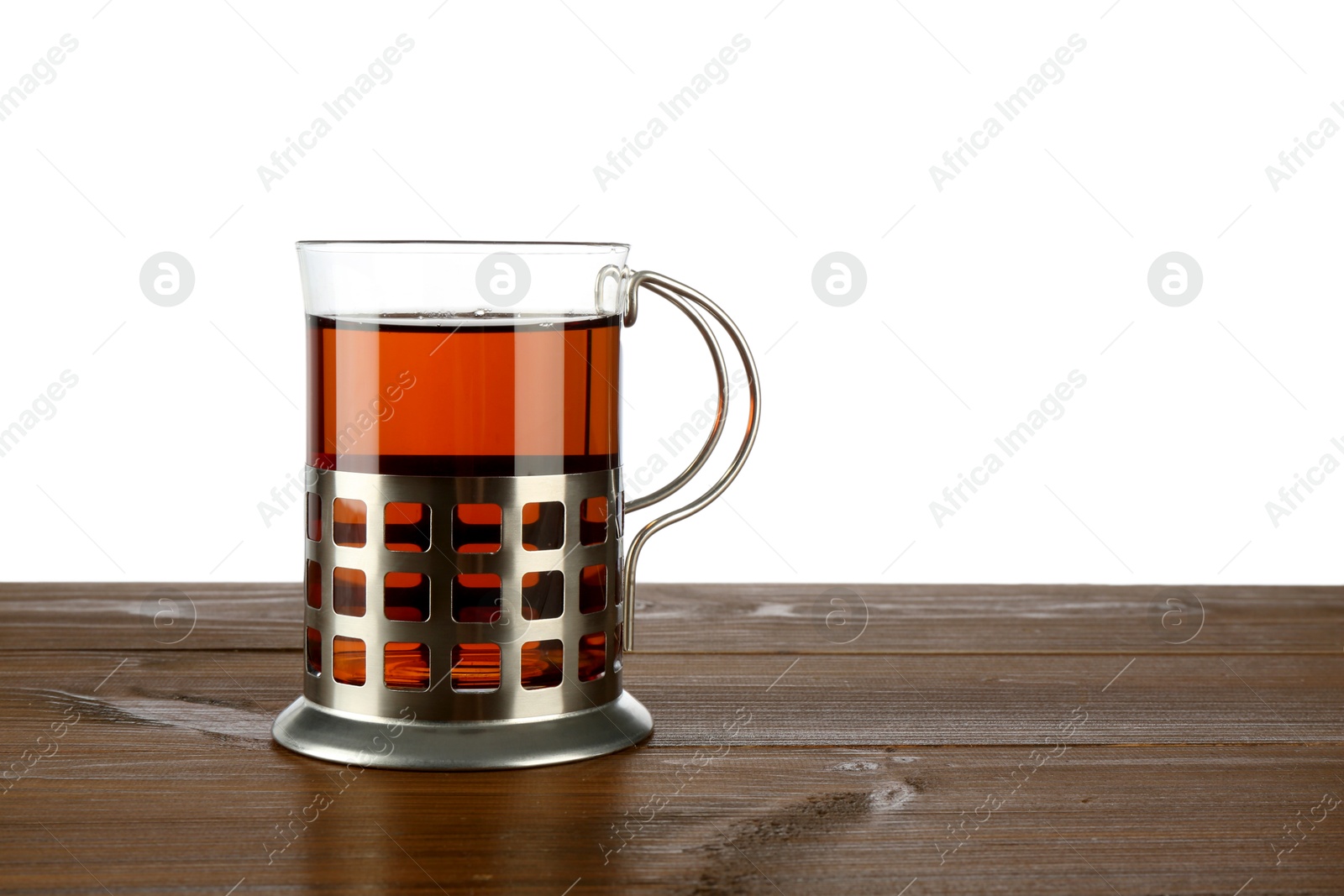 Photo of Glass of aromatic tea in holder on wooden table against white background