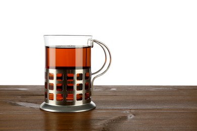 Photo of Glass of aromatic tea in holder on wooden table against white background