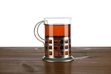 Photo of Glass of aromatic tea in holder on wooden table against white background