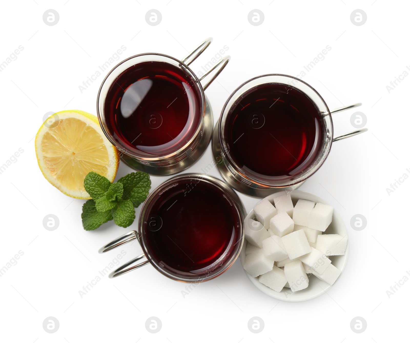 Photo of Glasses of aromatic tea in holders, lemon, sugar cubes and mint isolated on white, top view