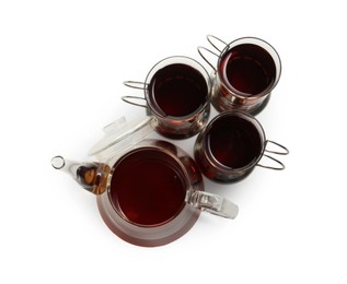 Photo of Glasses of aromatic tea in holders and teapot isolated on white, top view