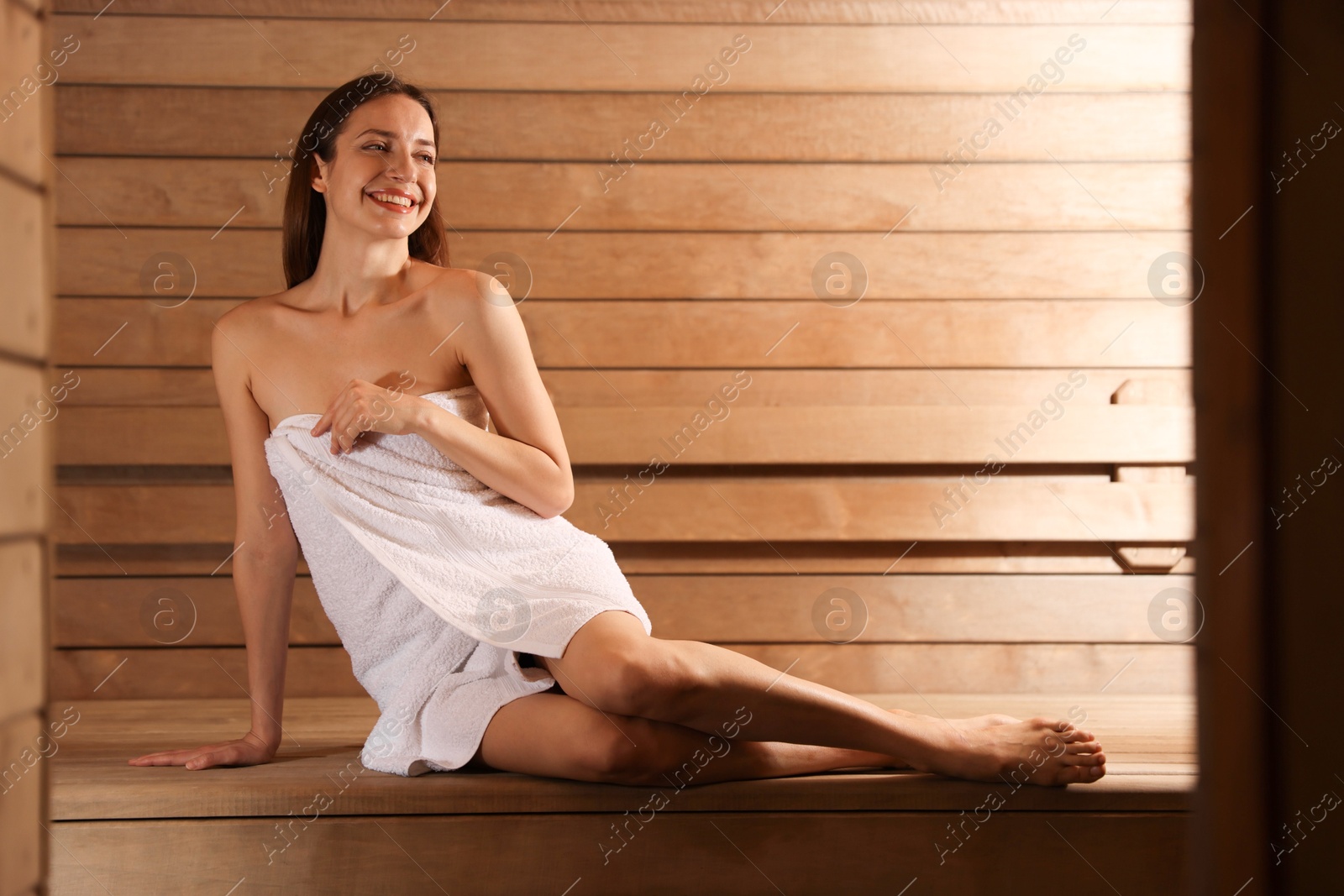 Photo of Smiling woman sitting on bench at sauna. Space for text