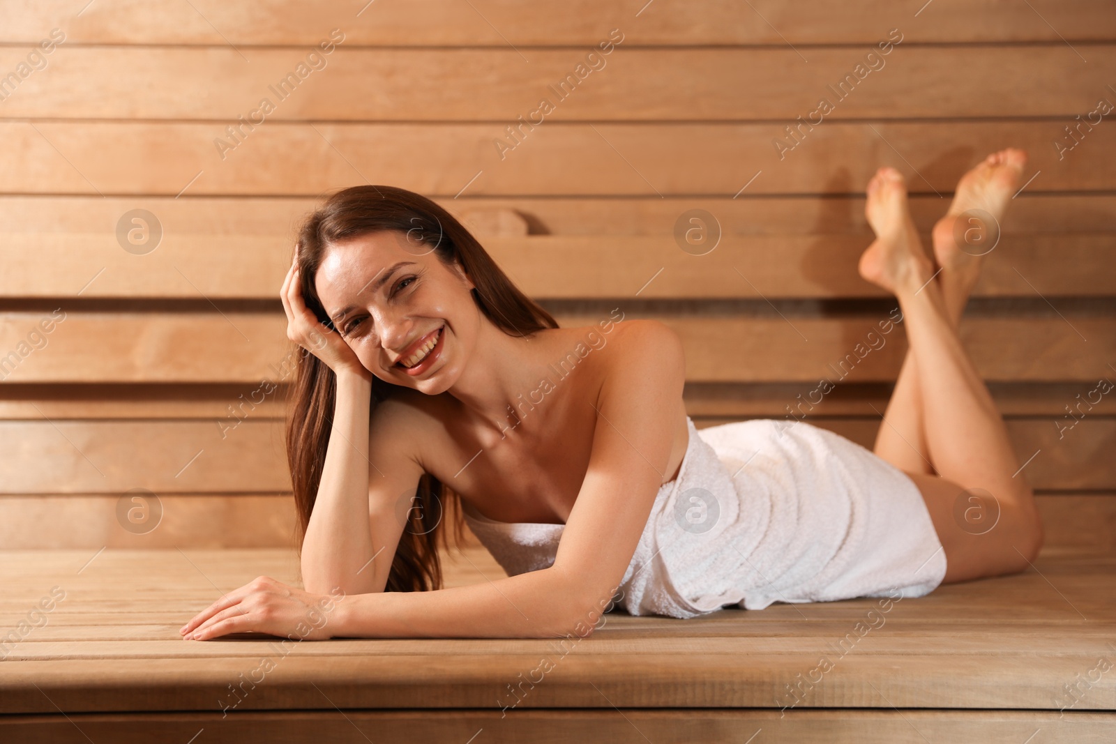 Photo of Smiling woman relaxing on bench at sauna