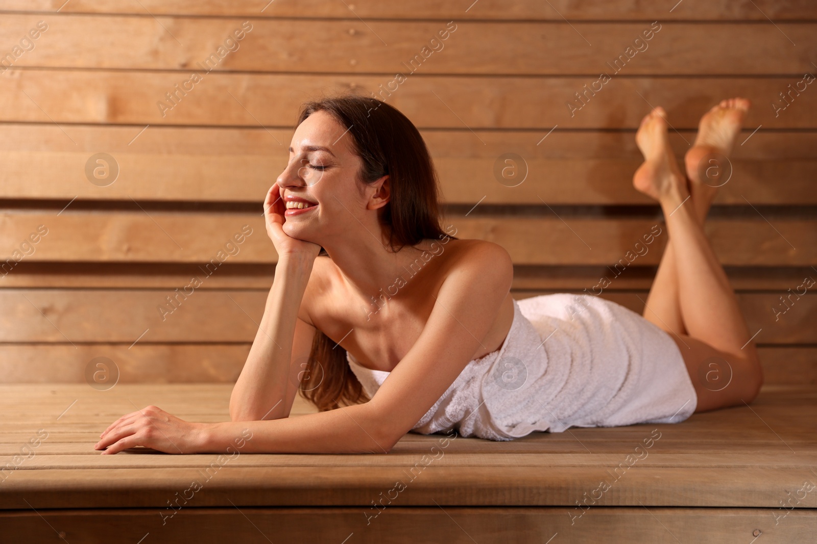 Photo of Smiling woman relaxing on bench at sauna