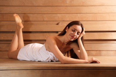 Beautiful woman relaxing on bench at sauna