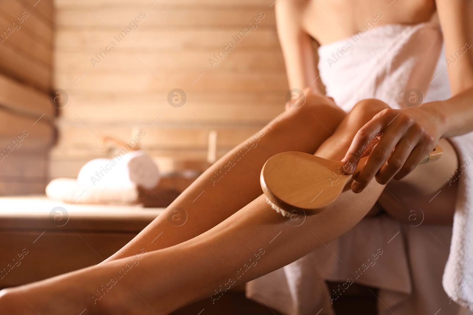 Photo of Woman massaging her leg with brush at sauna, closeup. Space for text