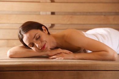 Beautiful woman relaxing on bench at sauna