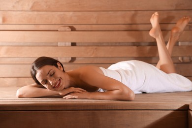 Photo of Smiling woman relaxing on bench at sauna