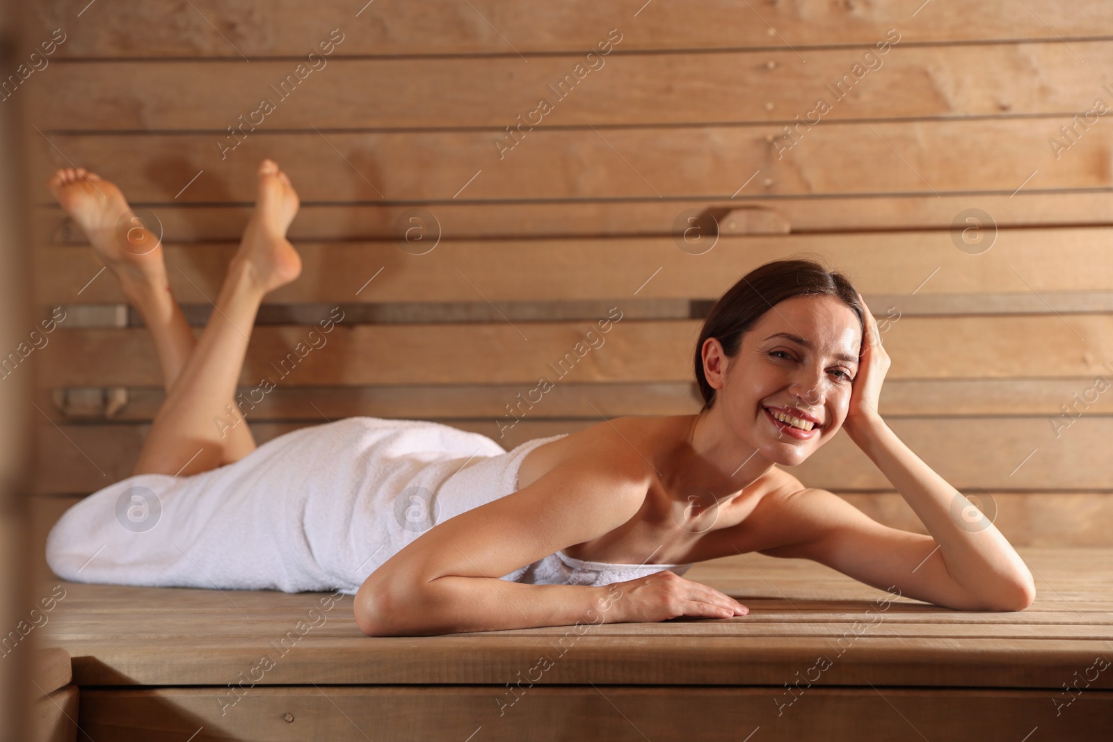 Photo of Smiling woman relaxing on bench at sauna