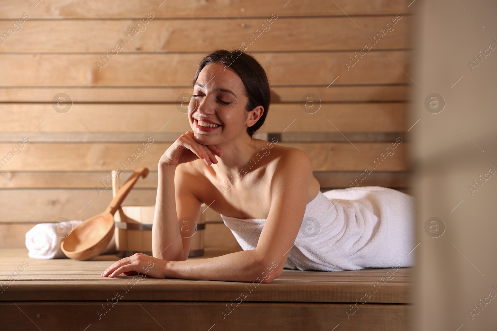 Photo of Smiling woman relaxing on bench at sauna