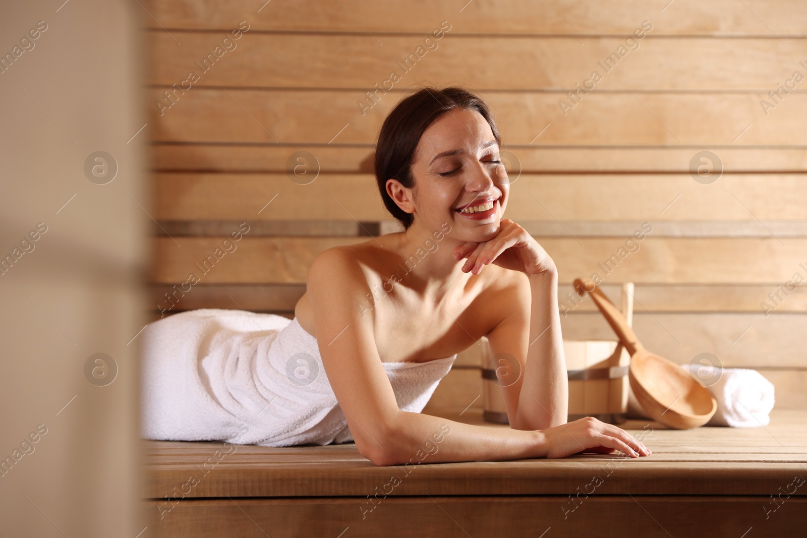 Photo of Smiling woman relaxing on bench at sauna