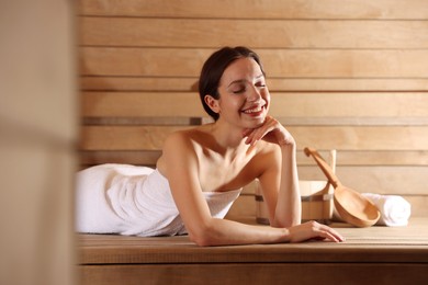 Photo of Smiling woman relaxing on bench at sauna