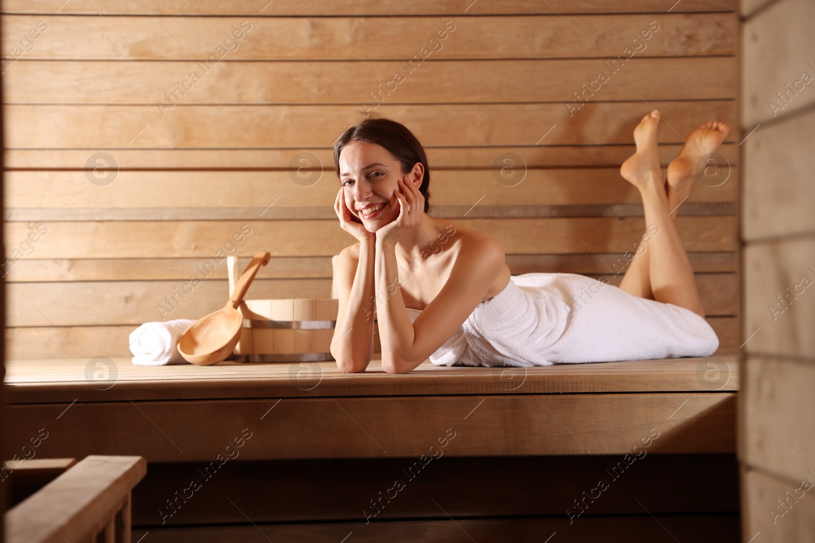 Photo of Smiling woman relaxing on bench at sauna