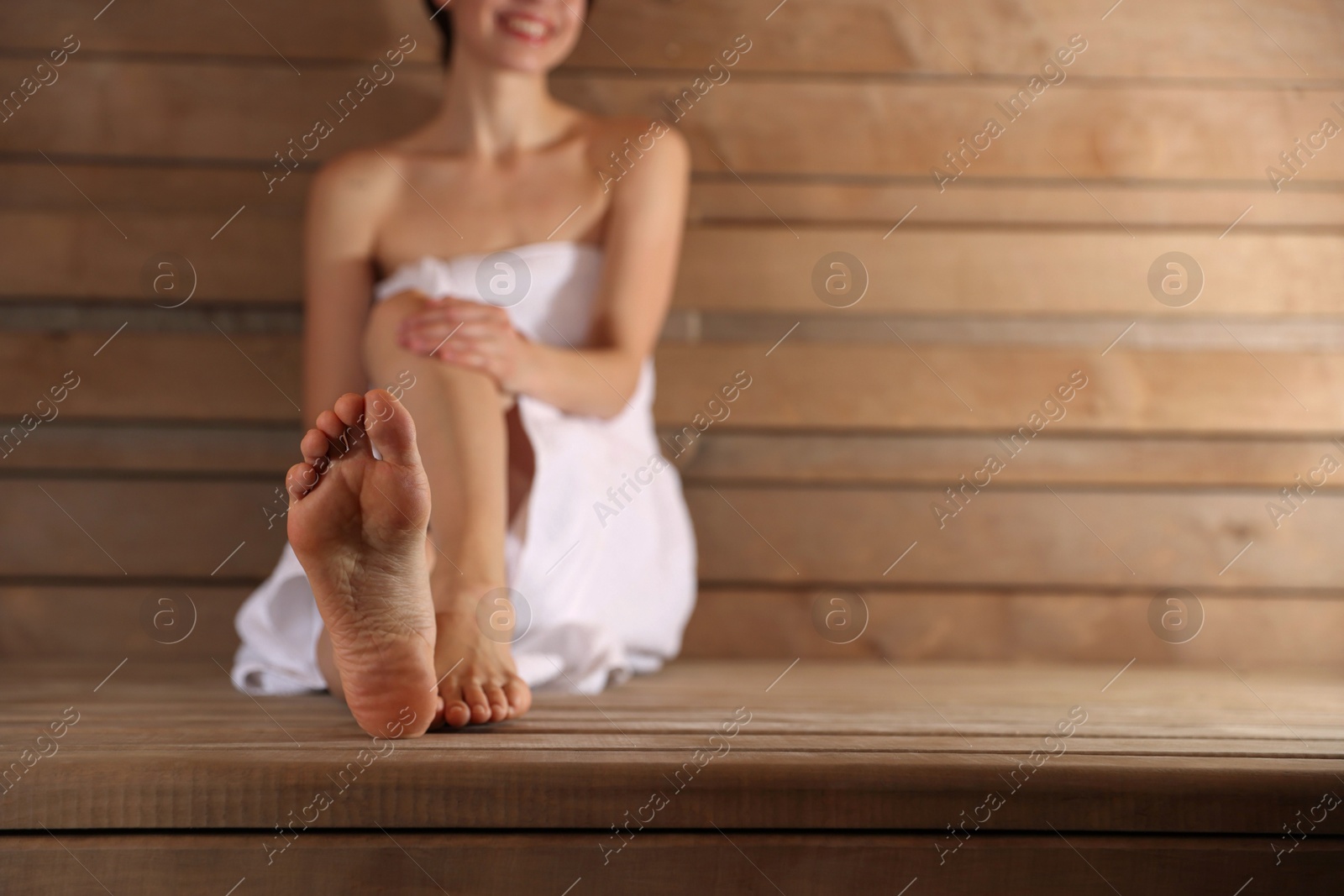 Photo of Smiling woman relaxing on bench at sauna, selective focus. Space for text