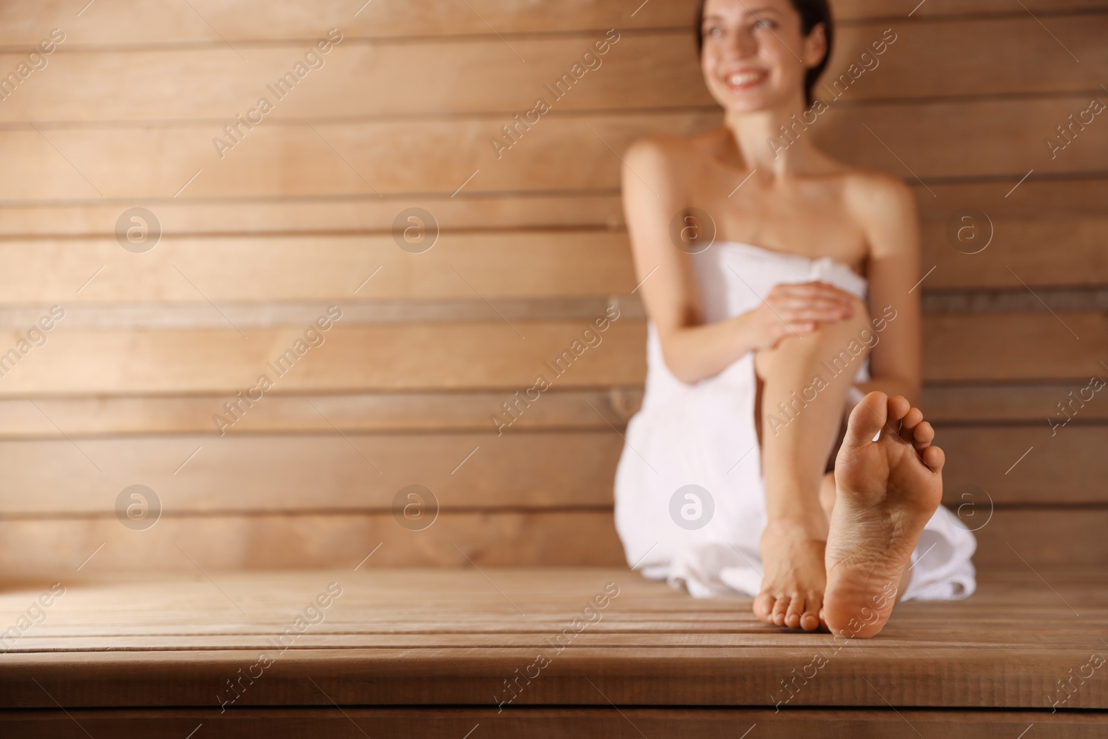 Photo of Smiling woman relaxing on bench at sauna, selective focus. Space for text