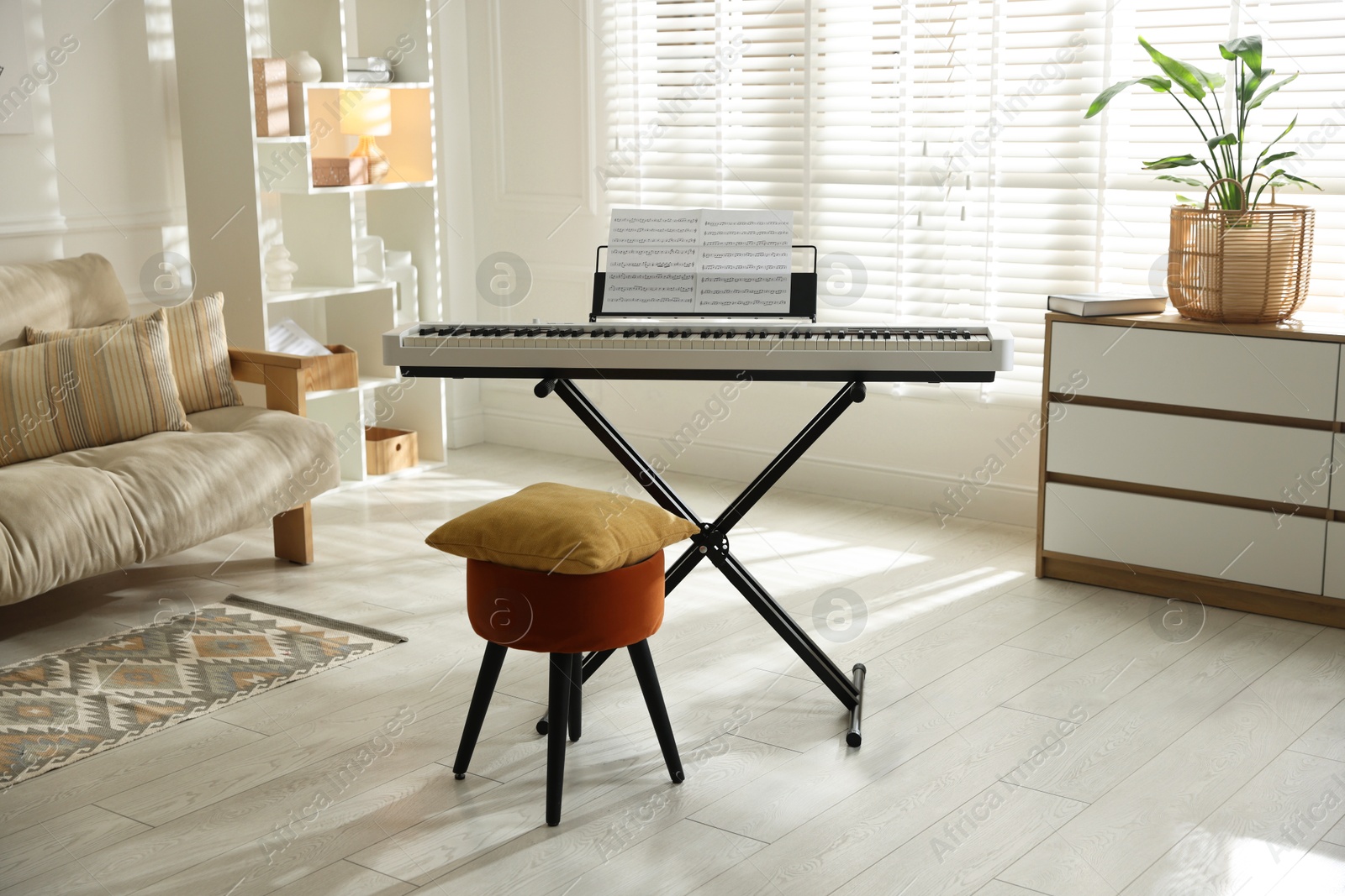 Photo of Synthesizer with music sheets, pouf and pillow indoors