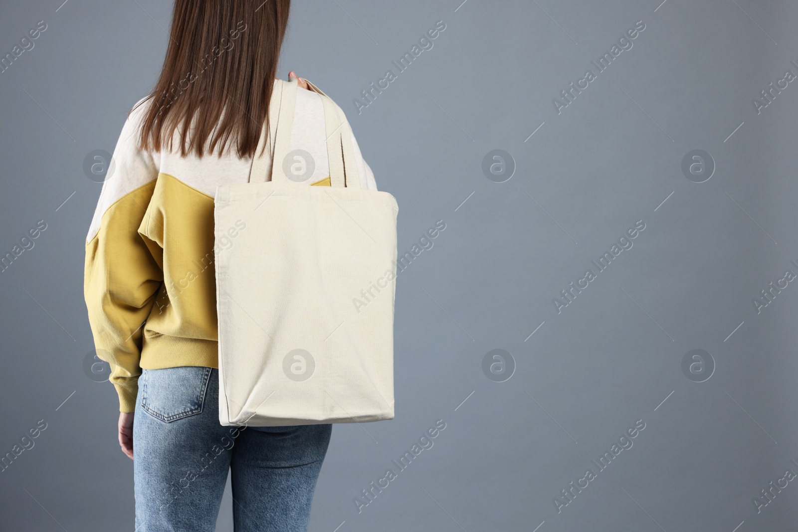 Photo of Woman with blank shopper bag on grey background, back view. Mockup for design