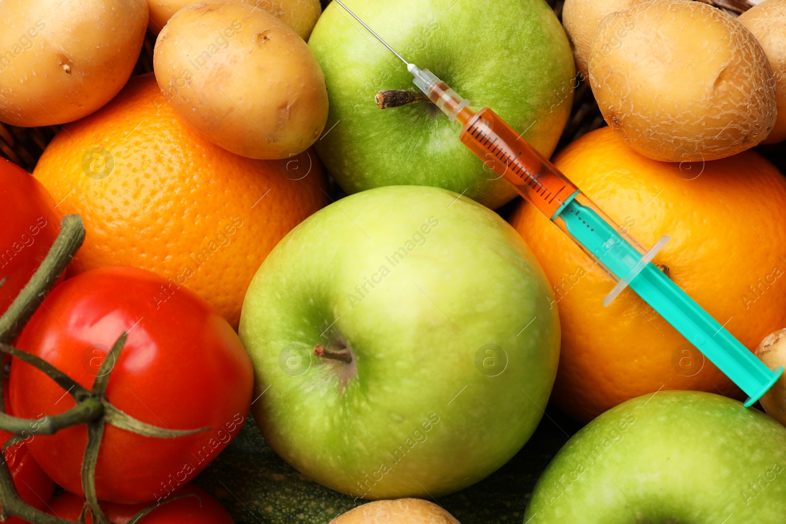 Photo of GMO concept. Different vegetables, fruits and syringe as background, top view