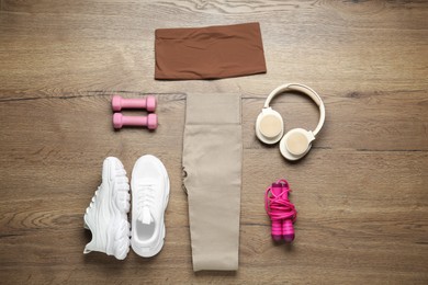 Photo of Flat lay composition with women's sportswear and athletic equipment on wooden background