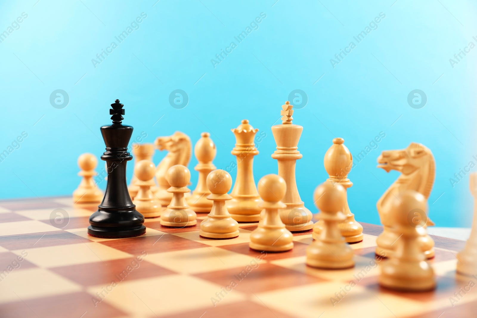 Photo of Black king in front of other white chess pieces on chessboard. Competition concept