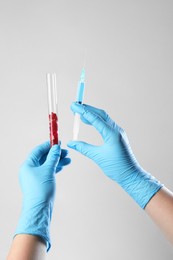 Photo of GMO concept. Scientist with syringe and piece of meat in test tube on white background, closeup