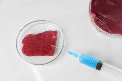 Photo of GMO concept. Piece of meat and syringe on light table, top view