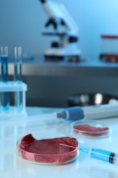 Photo of GMO concept. Piece of meat and syringe on table in laboratory