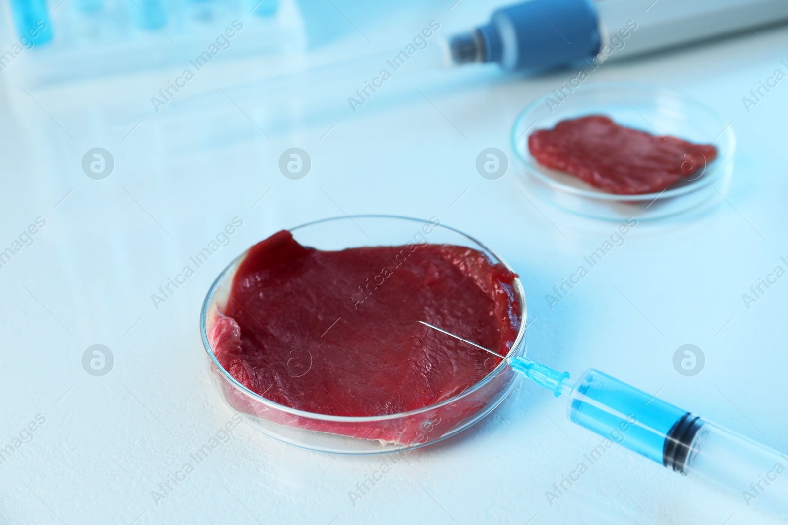 Photo of GMO concept. Piece of meat and syringe on table in laboratory