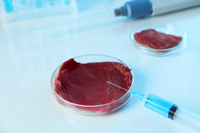 Photo of GMO concept. Piece of meat and syringe on table in laboratory