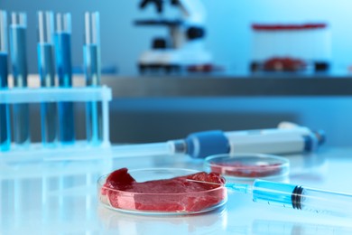 Photo of GMO concept. Piece of meat and syringe on table in laboratory. Space for text