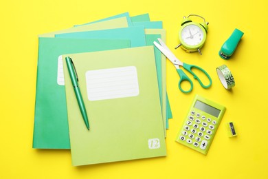 Photo of Flat lay composition with copybooks and other school stationery on yellow background