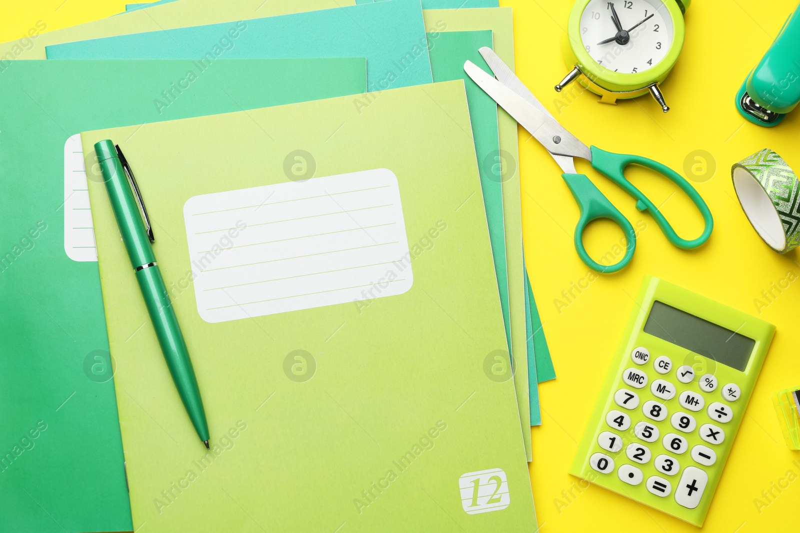 Photo of Flat lay composition with copybooks and other school stationery on yellow background