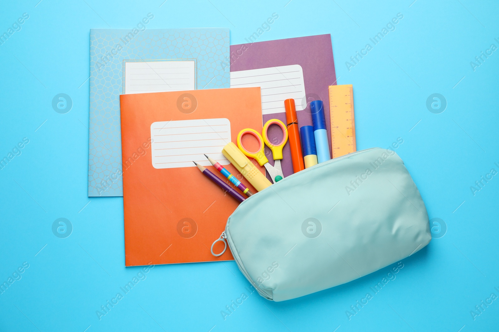 Photo of Colorful copybooks and other school stationery on light blue background, flat lay