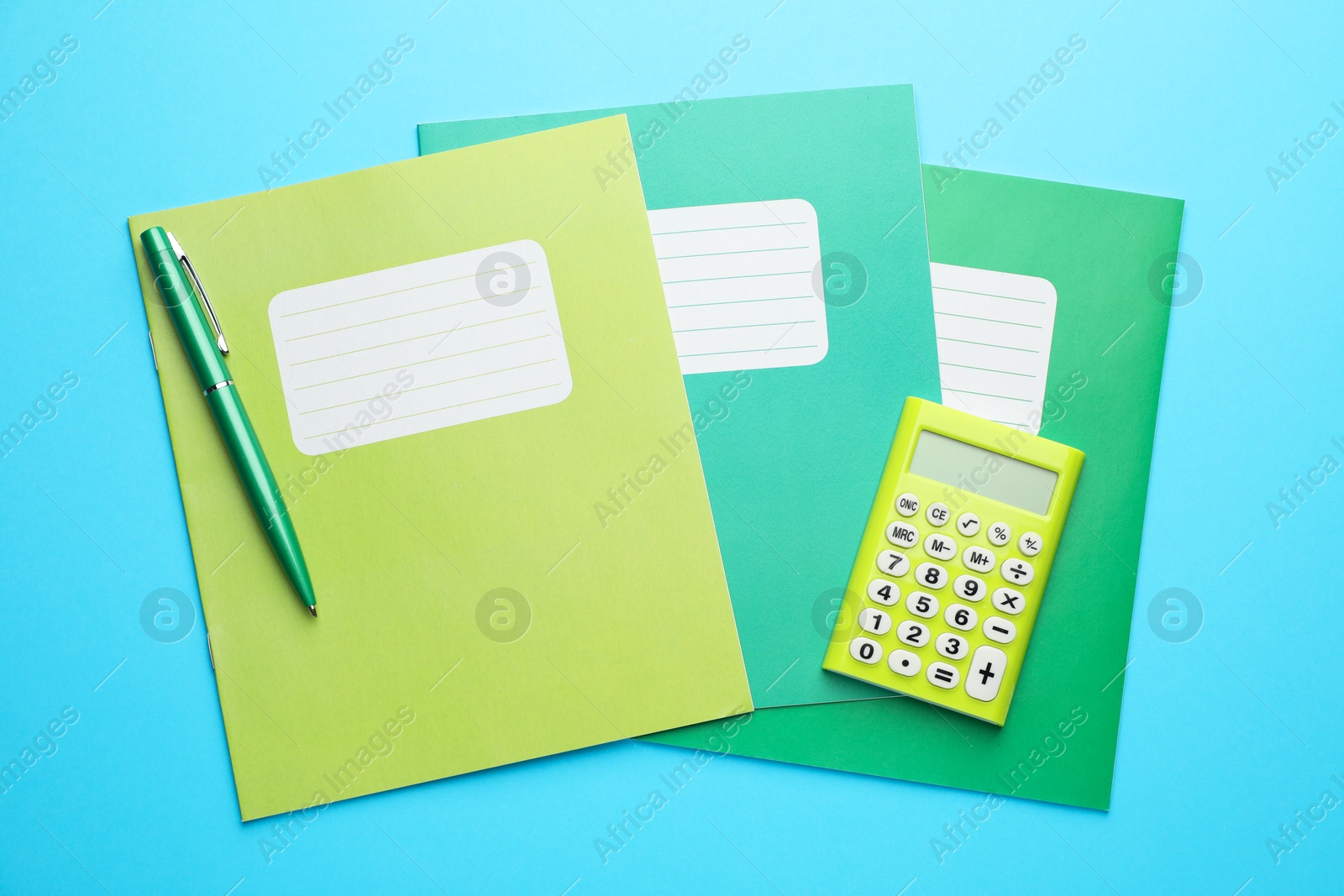 Photo of Copybooks, calculator and pen on light blue background, top view