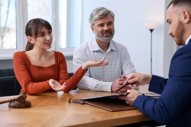 Couple having meeting with professional notary at wooden desk indoors