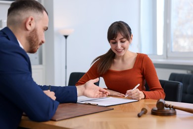 Client signing notarial paperwork during meeting with lawyer at wooden desk indoors