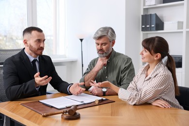 Photo of Couple having meeting with professional lawyer at wooden desk indoors