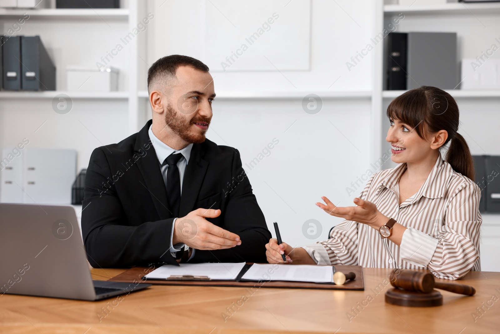 Photo of Woman having meeting with professional notary at wooden desk indoors