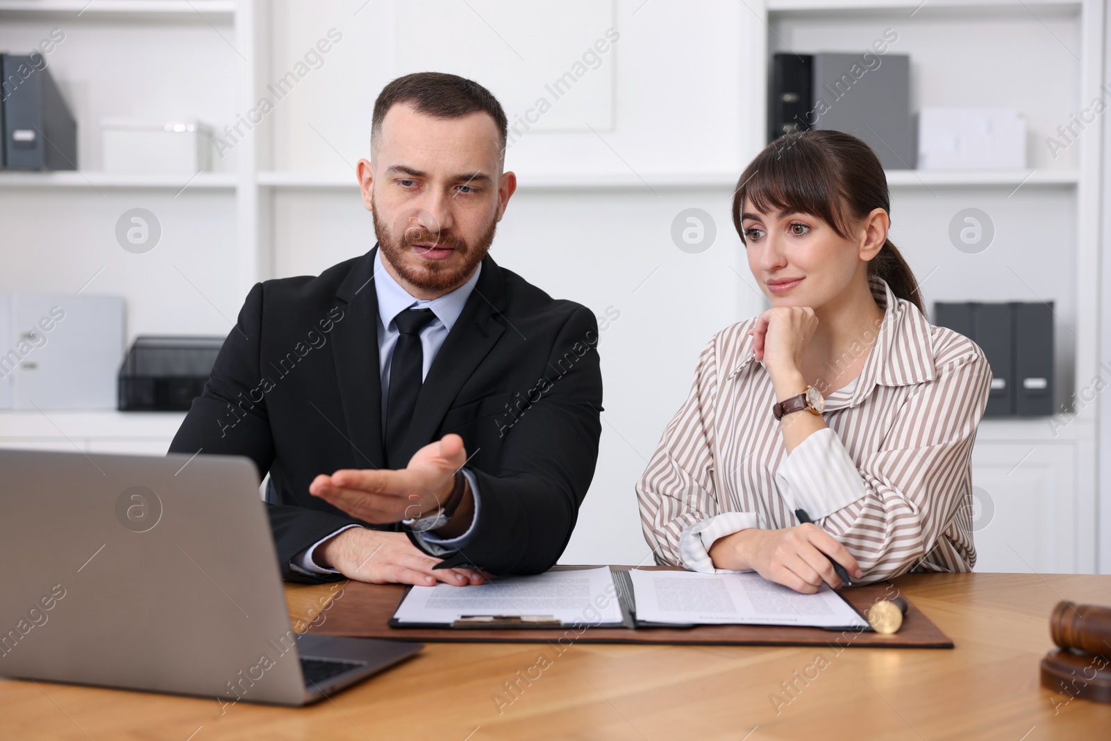 Photo of Woman having meeting with professional notary at wooden desk indoors