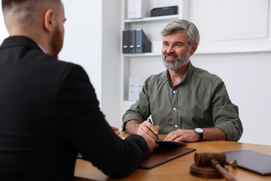 Photo of Man having meeting with professional lawyer at wooden desk indoors