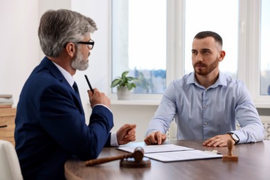 Photo of Man having meeting with professional lawyer at wooden desk indoors