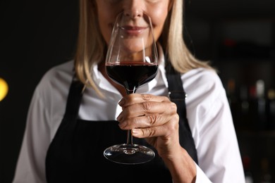 Photo of Professional sommelier tasting red wine indoors, closeup