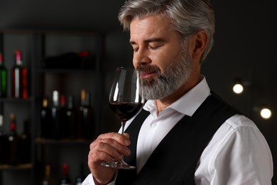 Professional sommelier tasting red wine in glass indoors